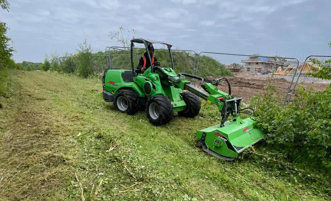An operative processing felled timber with a chainsaw during woodland vegetation clearance