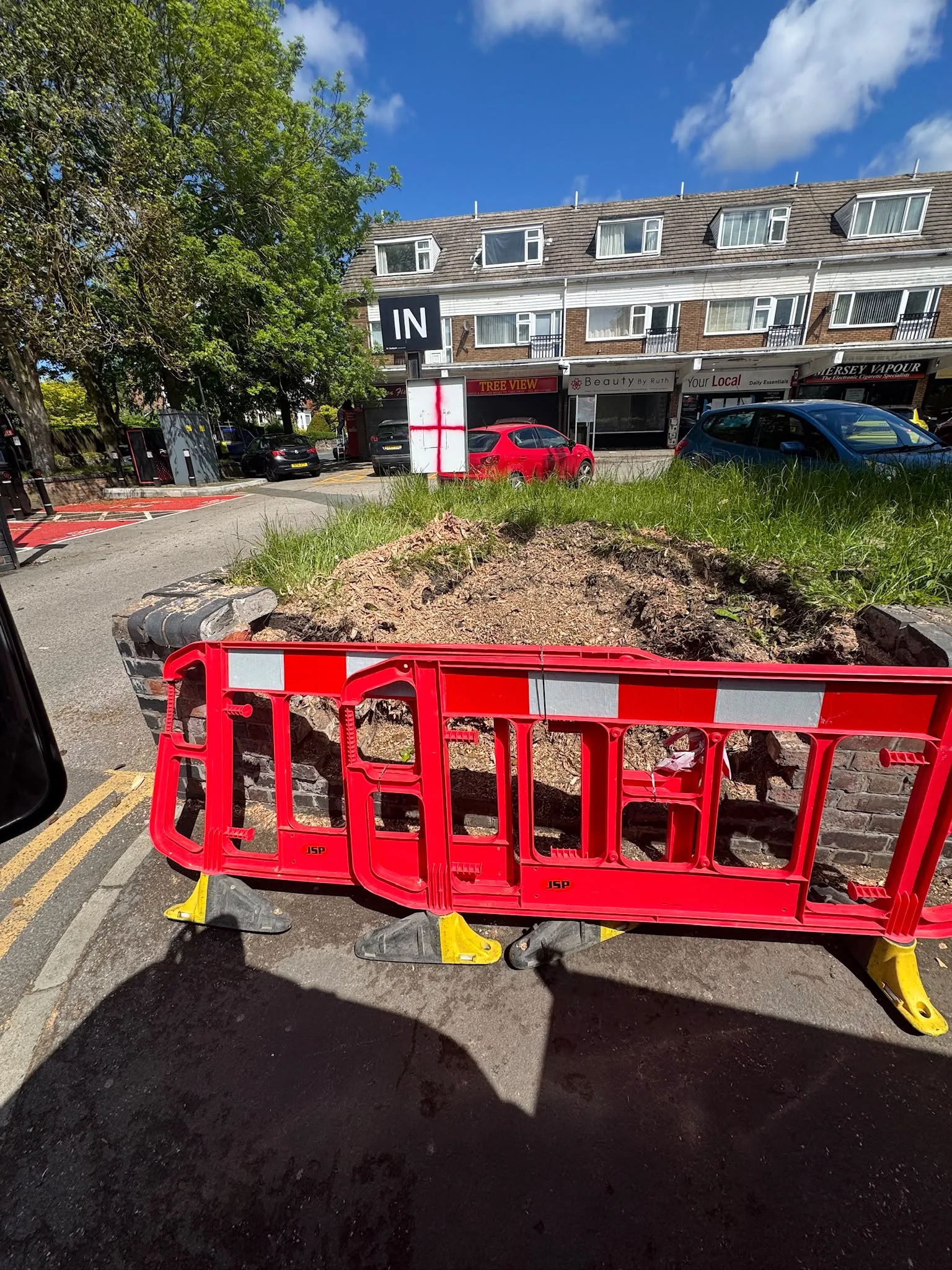 A work area cordoned off with pedestrian barriers on a residential street during tree works
